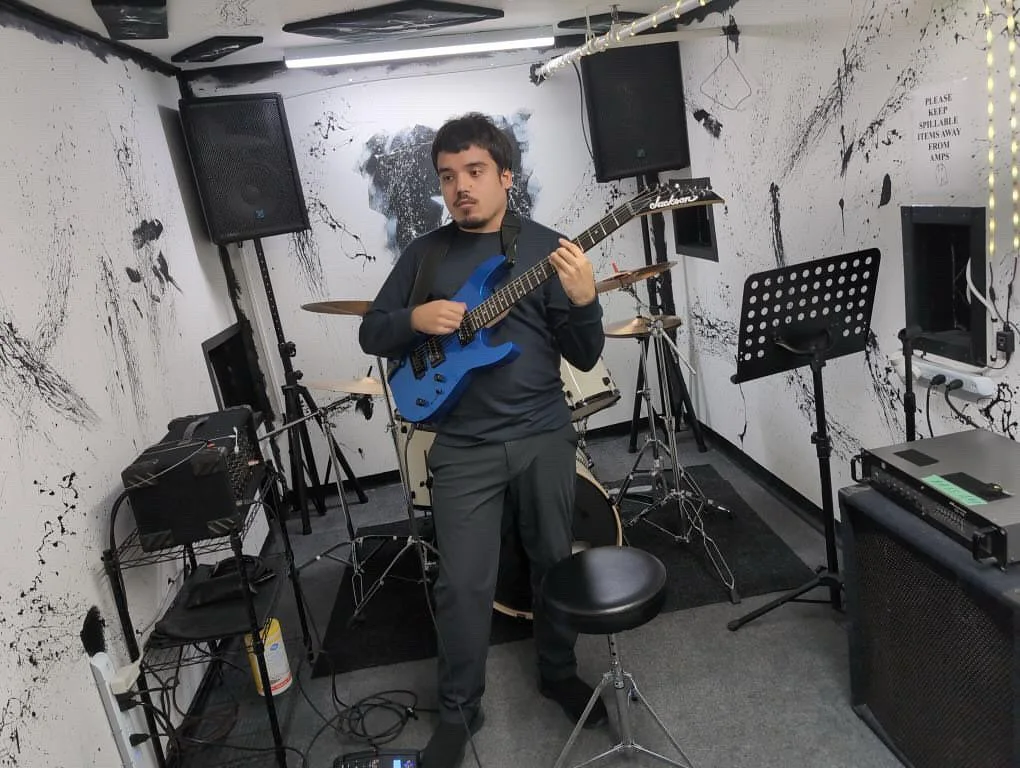 This is a self-portrait photograph of Justin Bento playing guitar in a studio.
